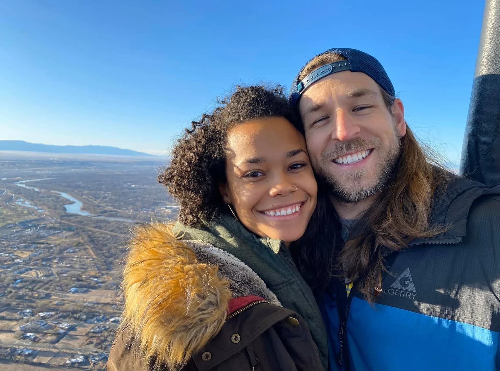 Two smiling passengers sharing a hot-air balloon ride above Albuquerque