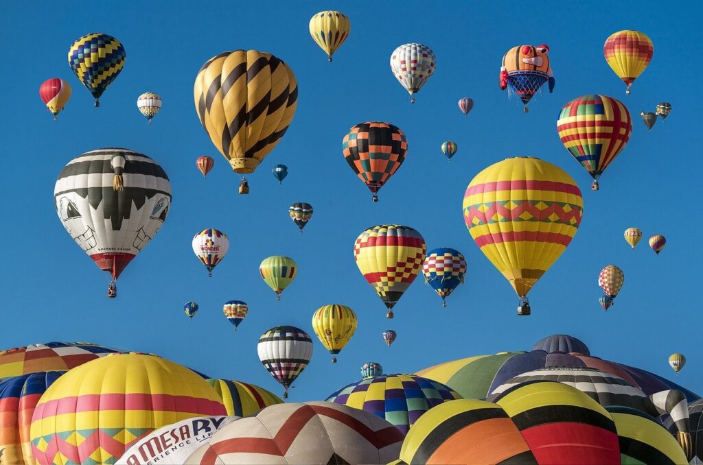 A colorful collection of hot air balloons floats in a perfect blue sky.
